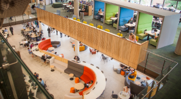 The Kingswood campus Library interior is shown with colourful couches and study booths. Students study in groups and individually.